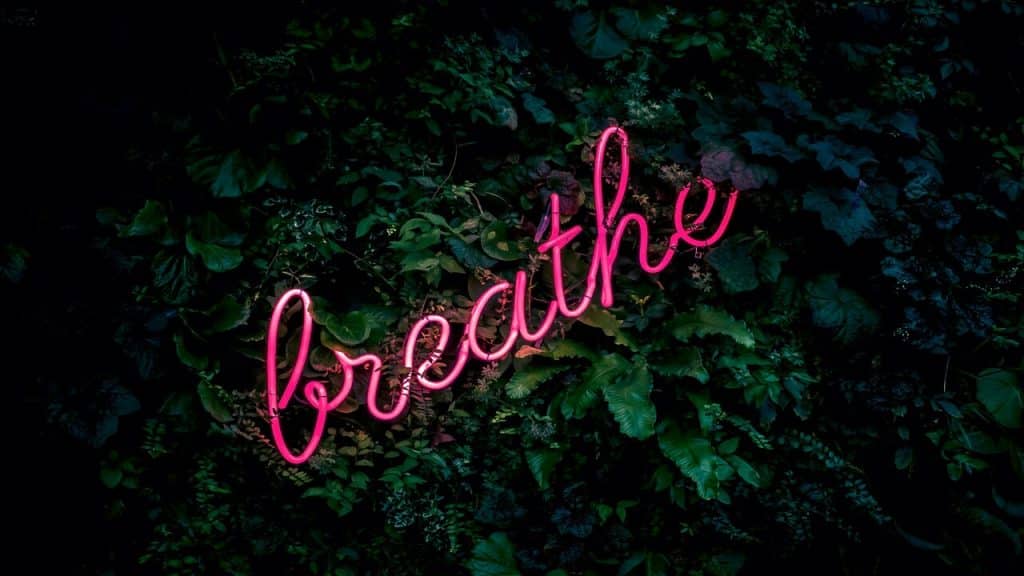 A neon light saying “breathe”