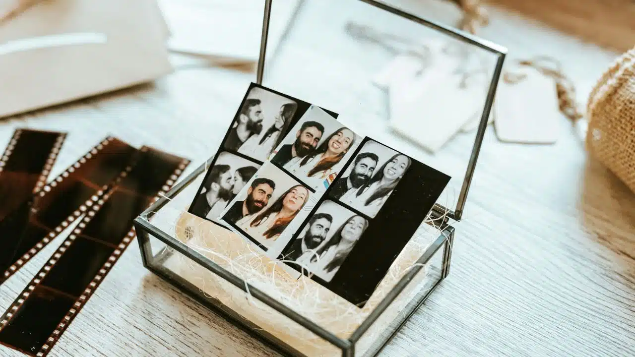 A clear box holds several black and white photo booth strips of a couple.