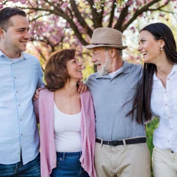 A well dressed man greeting an older couple at a family gathering.