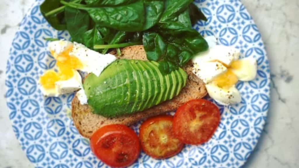 A well balanced meal on a plate including eggs, greens and carbs.