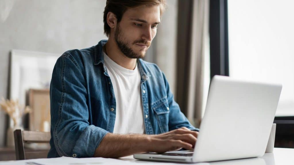 A man typing on a laptop at a desk.