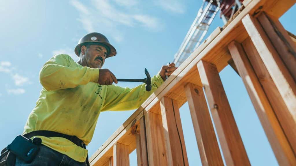 A construction worker hammering wood framing.