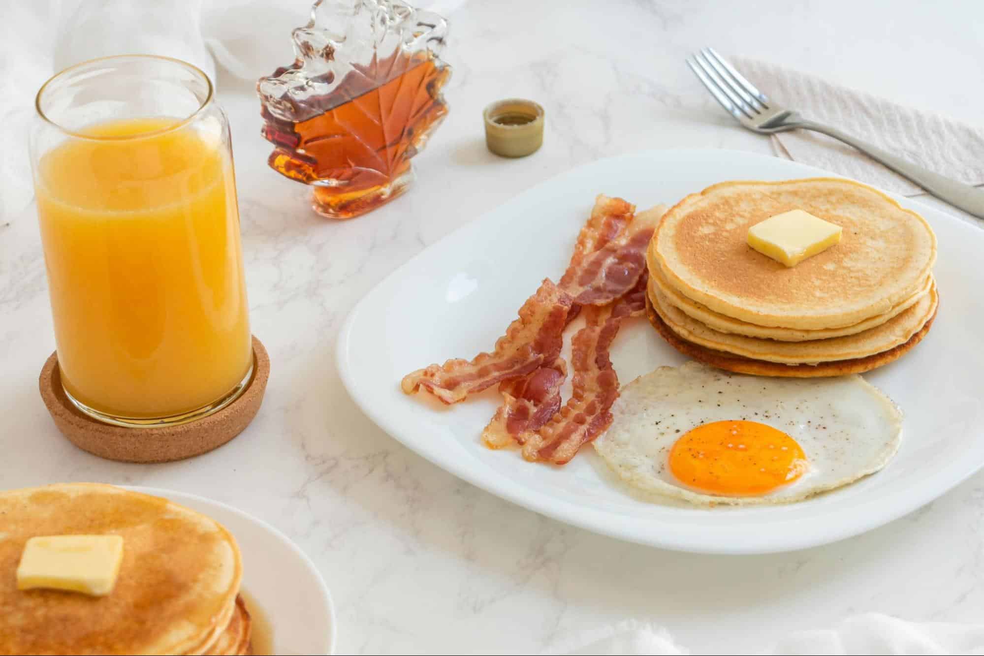 A picture of pancake with eggs and bacon.