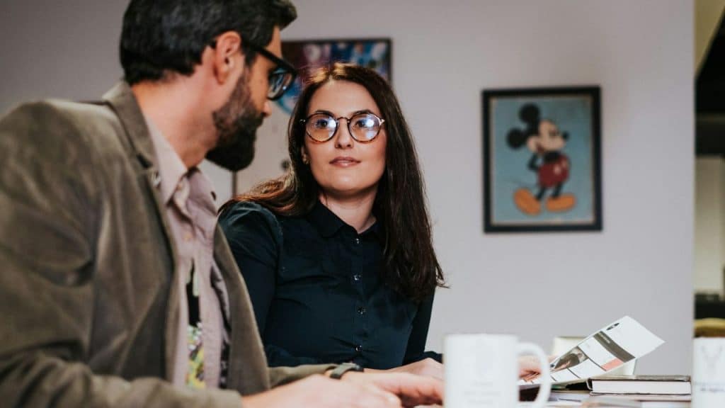 A woman in glasses looks attentively at a man during a meeting.