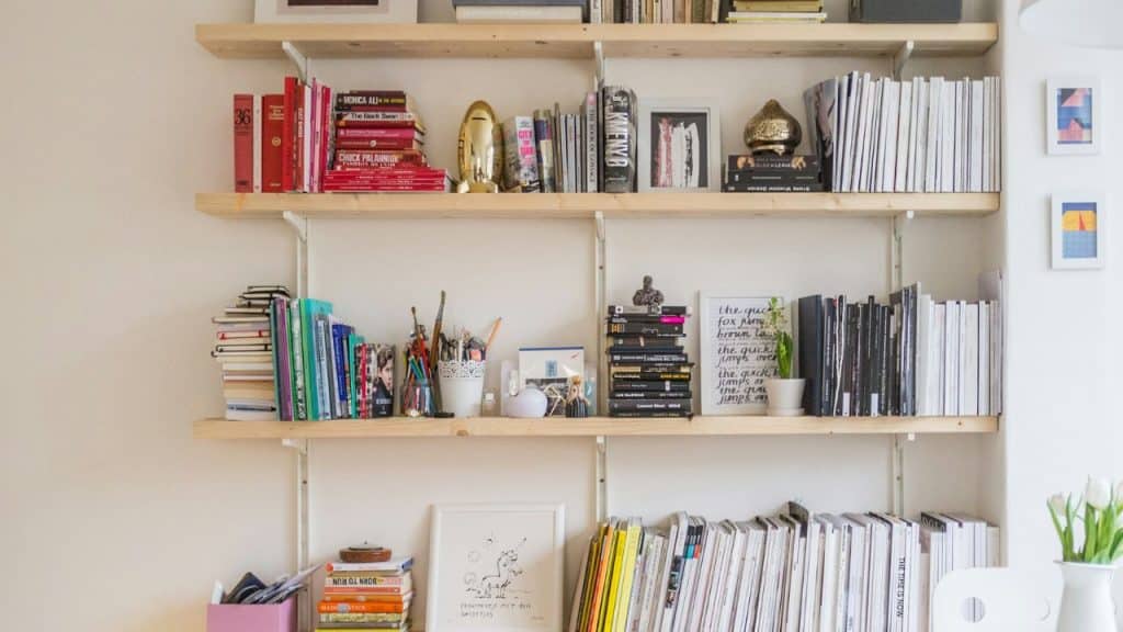 A full-frame shot of three wooden shelves packed with books and decorative items.