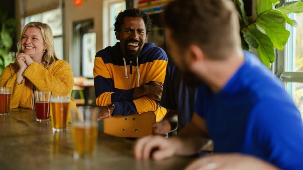 A group of friends laughing at a bar counter.