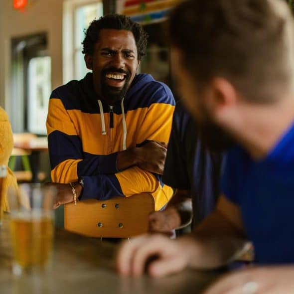 A group of friends laughing at a bar counter.