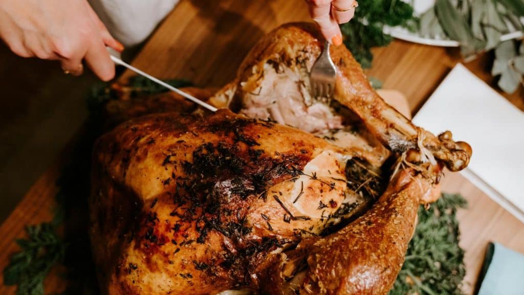 A person carving a roasted turkey.