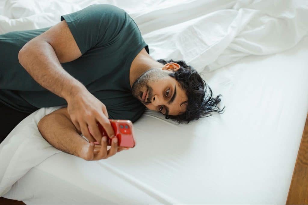 A man using cellphone while laying on the bed