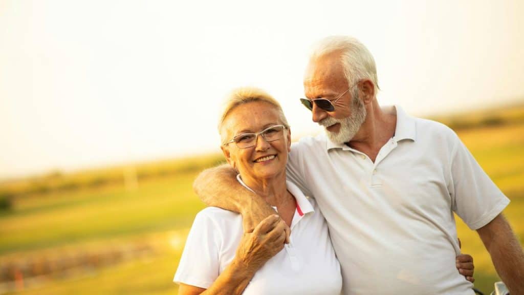 A senior couple embracing on a sunny field.