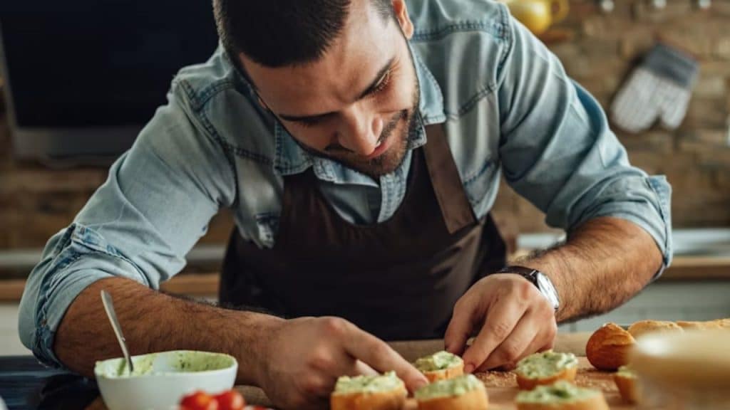 Man quietly preparing a meal while his partner relaxes nearby