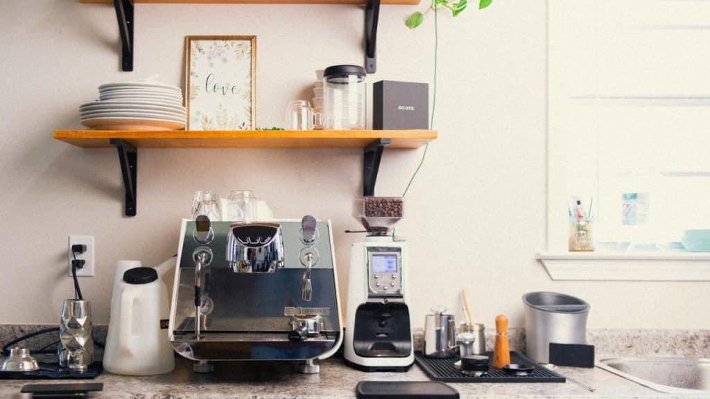 A coffee bar with an espresso machine and grinder on a kitchen counter.