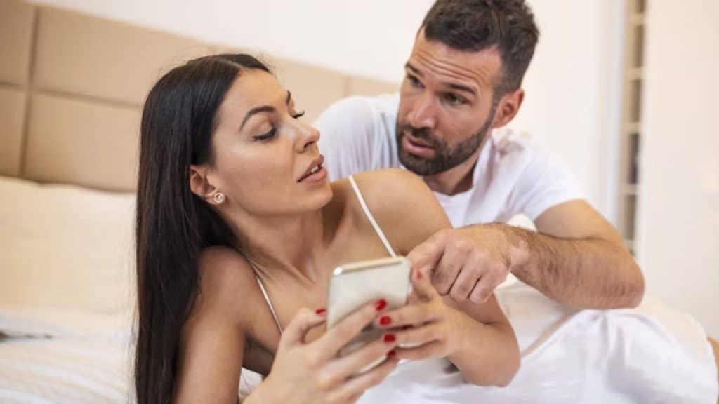 Man appearing suspicious while looking over a woman’s phone