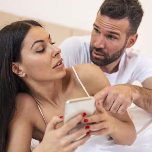 Man appearing suspicious while looking over a woman’s phone