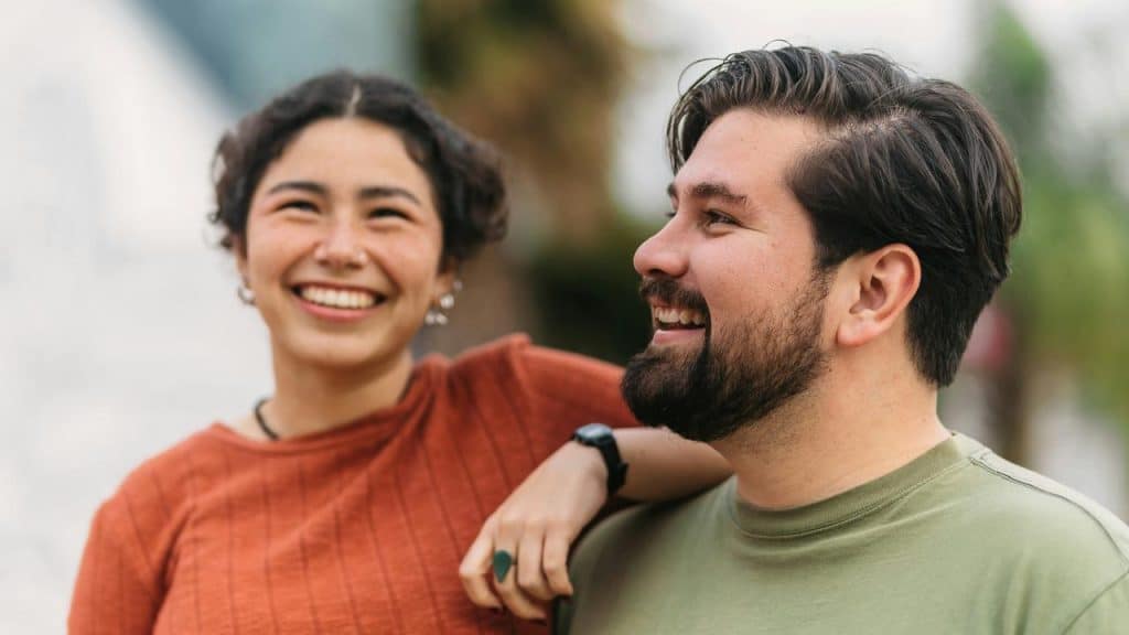 A smiling couple standing close together outdoors.