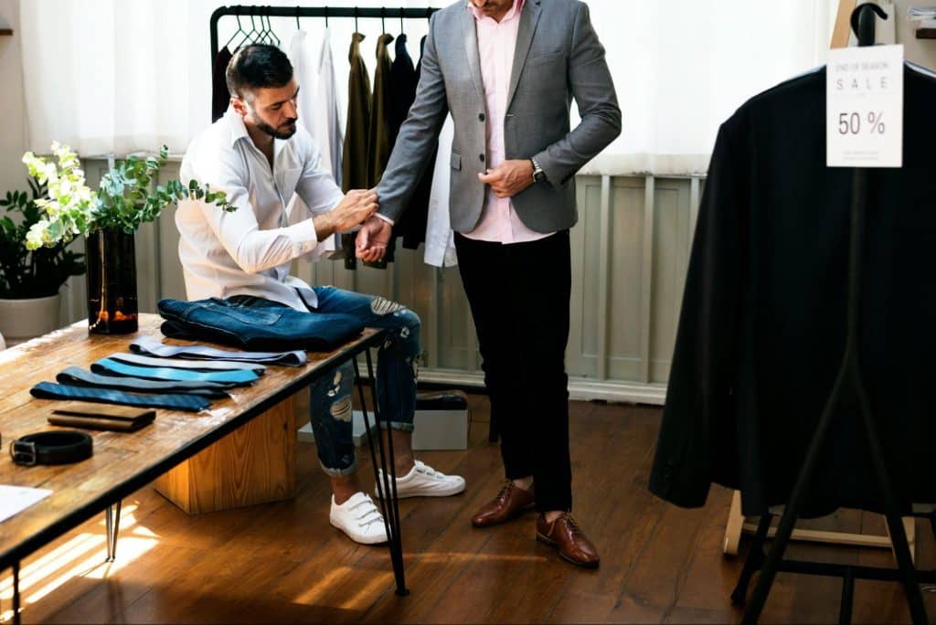 A man getting help to fix his suit.