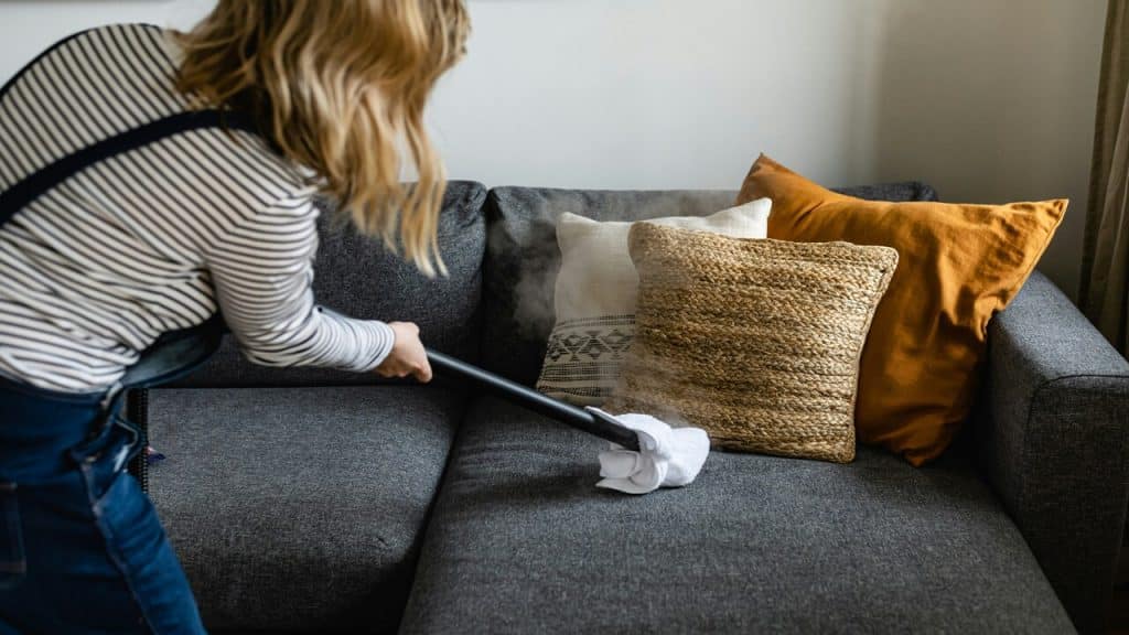 A woman vacuuming her couch
