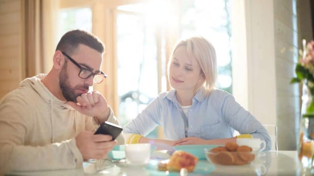 Couple  reviewing household emergency fund status on phone app.