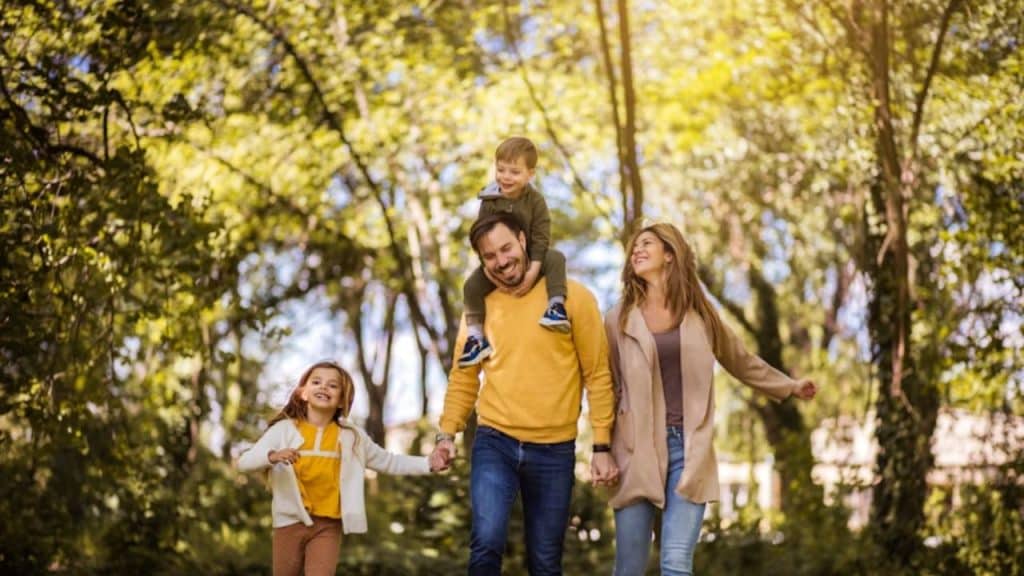 Father laughing and hugging his children during outdoor playtime.