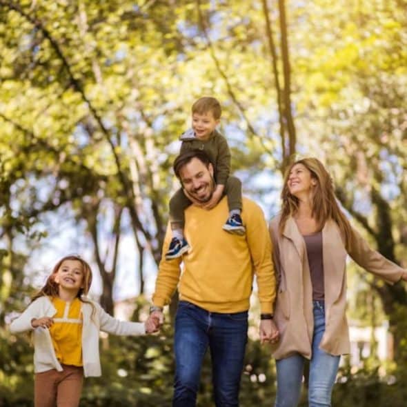 Father laughing and hugging his children during outdoor playtime.