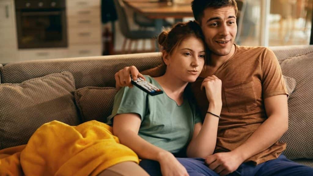 Couple watching a show together on the couch.