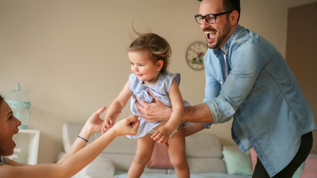 A father lifting his toddler toward a woman’s outstretched hands.