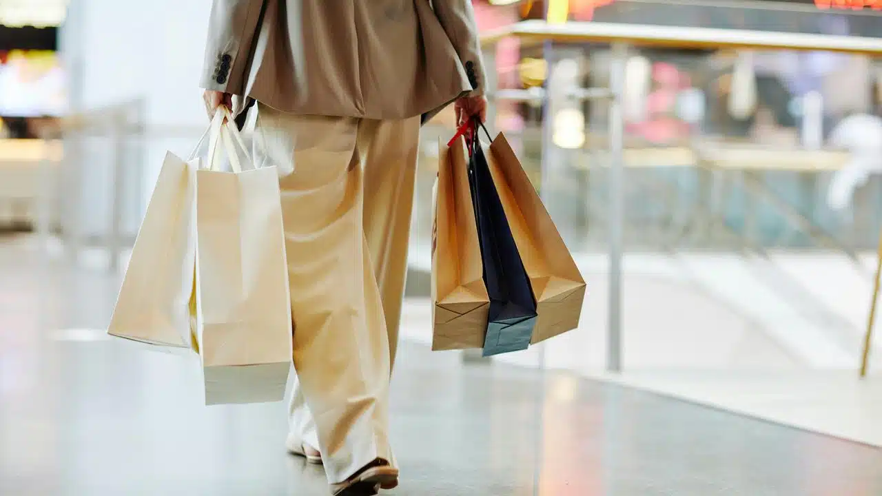 A person carrying shopping bags in a mall.