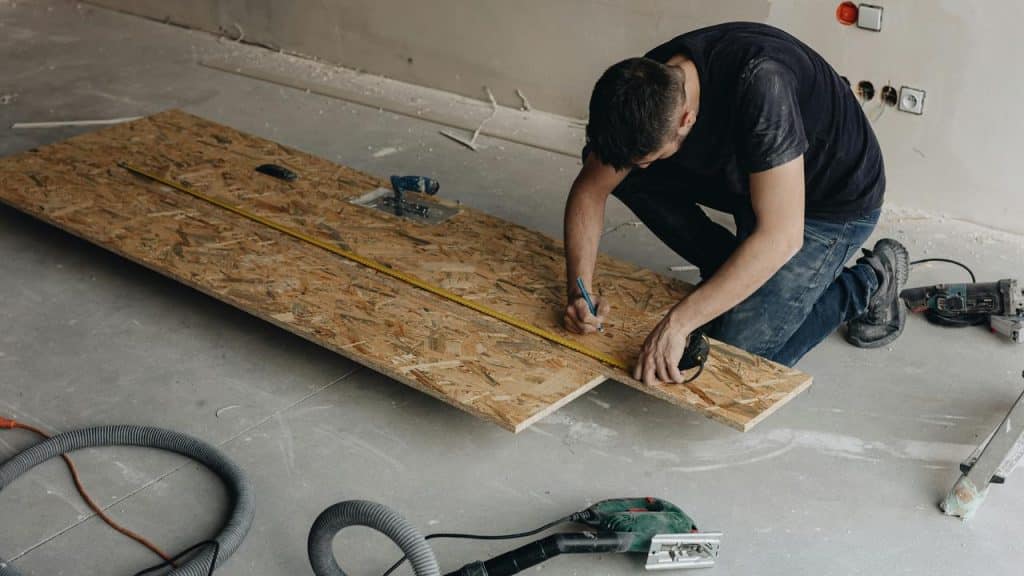 A man measuring and marking a wooden board.