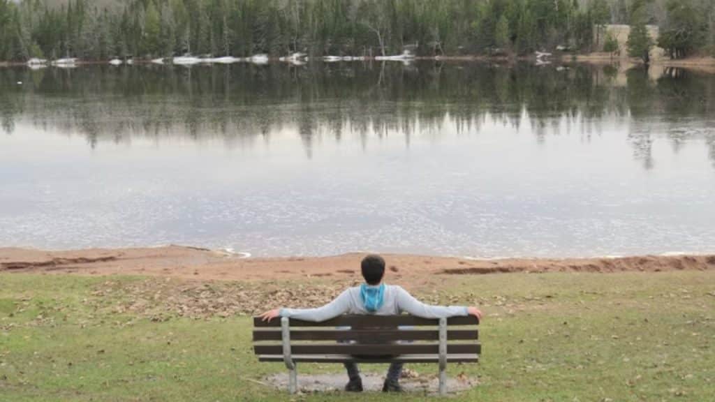 A man thinking quietly by a lakeside cabin