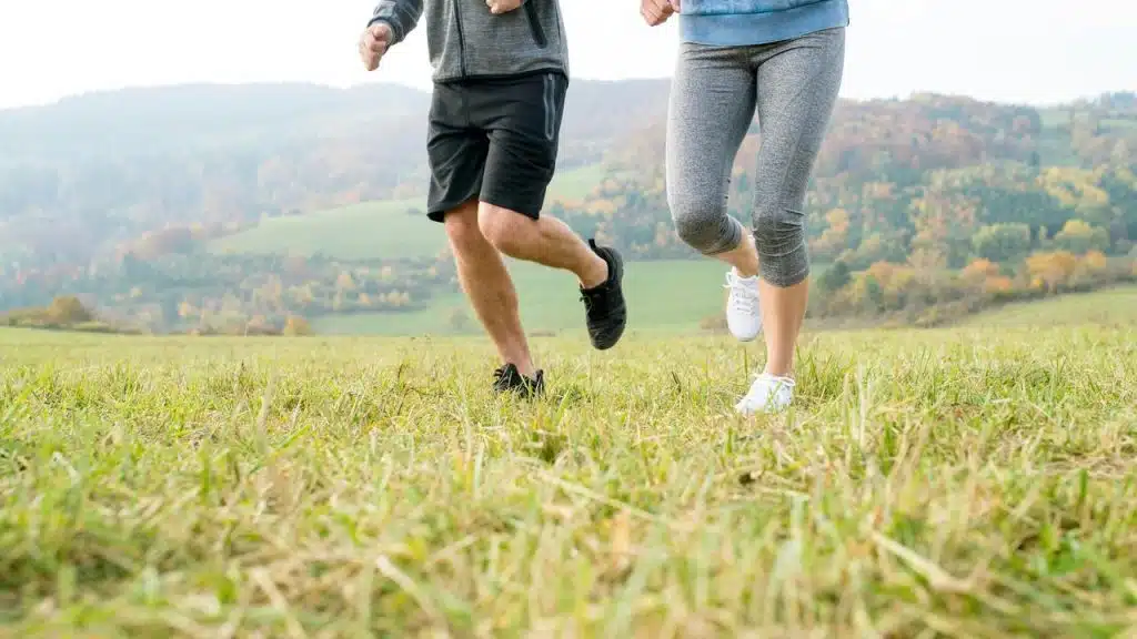 A couple jogging in a grassy field.