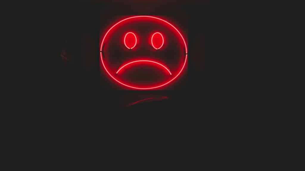 A neon light of a sad emoji