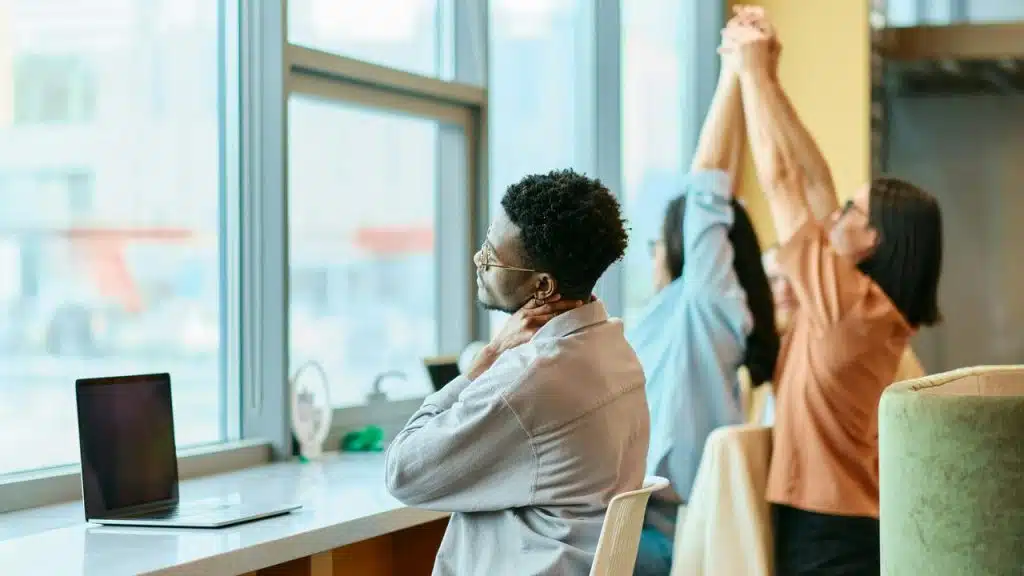 A group of office workers stretching by a window.