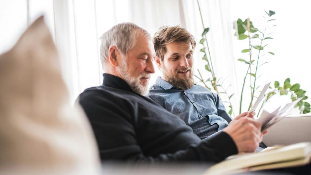 A younger man and an older man reading papers together.