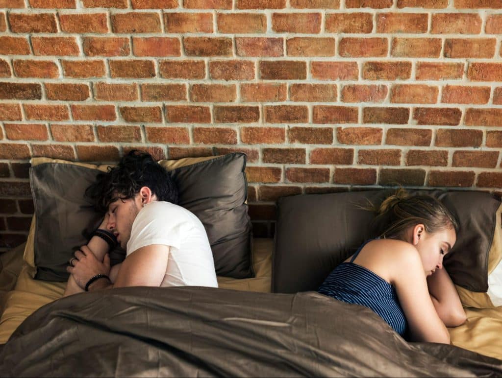 A man and woman sleeping but facing away from each other