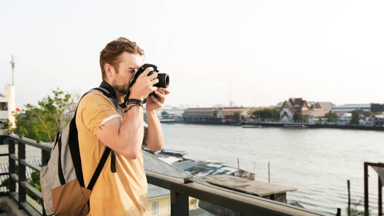 A man exploring and taking pictures at a coastal town alone with a backpack.