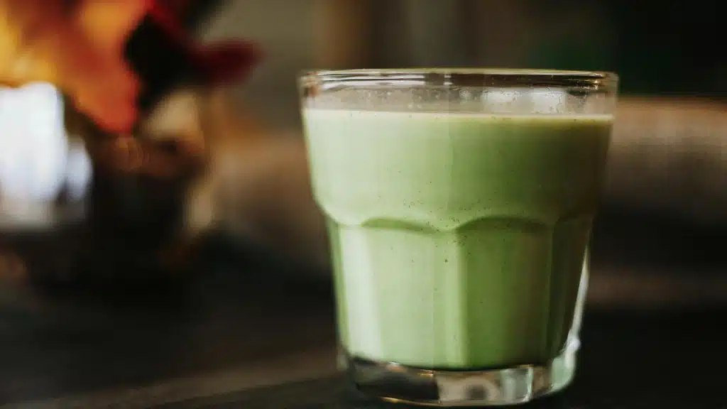 A creamy green smoothie in a clear glass.