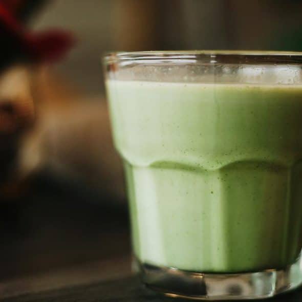 A creamy green smoothie in a clear glass.