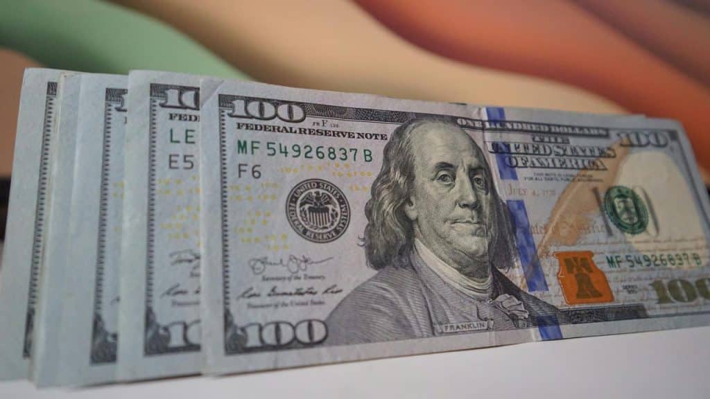 A stack of U.S. $100 bills fanned out on a surface.