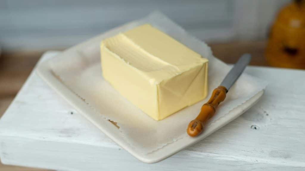 A stick of butter on a dish with a butter knife.