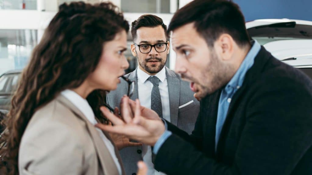 A man and woman arguing intensely as another man watches.
