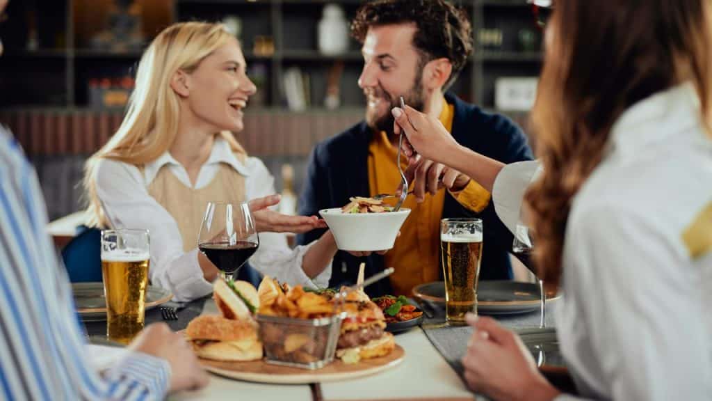 A group of friends sharing food and drinks at a restaurant table.