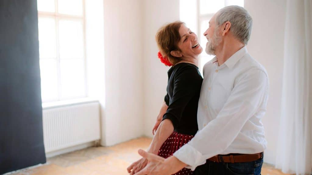 An elderly couple dancing joyfully indoors.