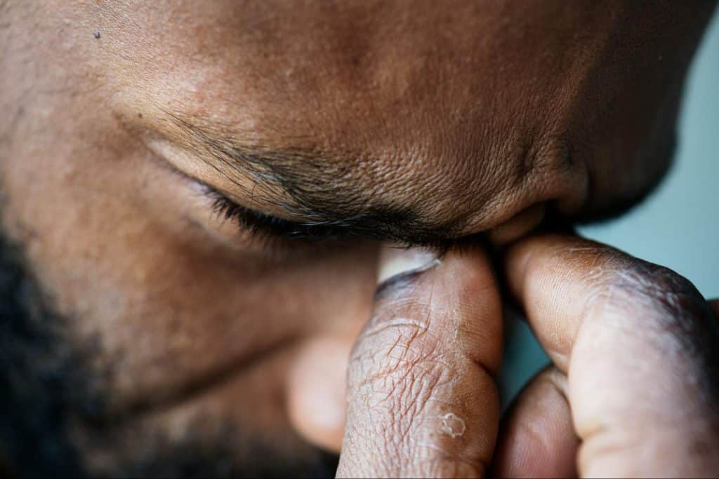 A man pinching the part of the face between the eyes
