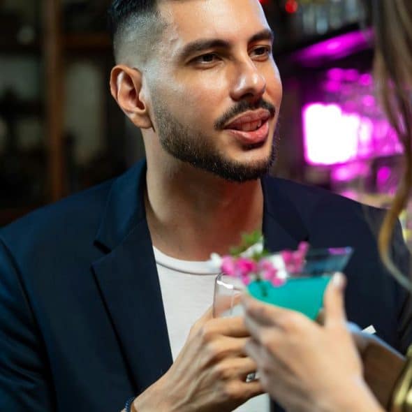 A man in a blue blazer talking to a woman inside a bar.