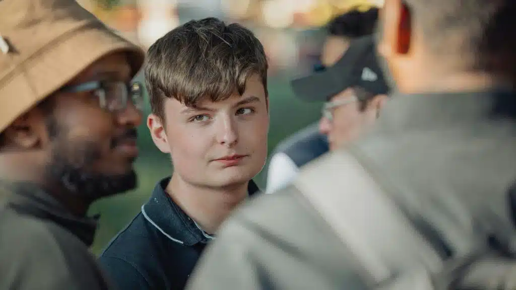 A young man listening to friends in conversation.