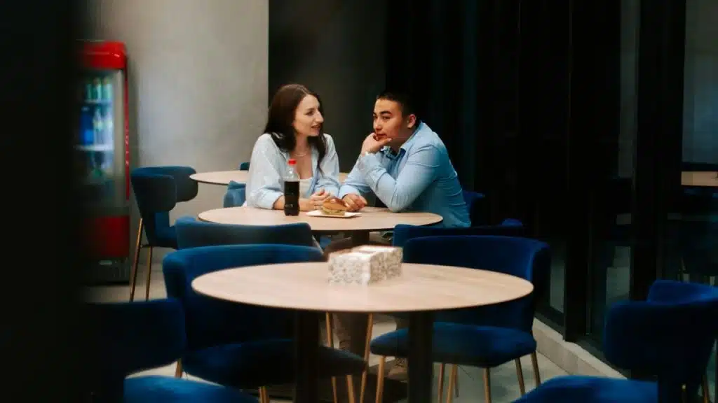 A man and a woman sit at a round table in a cafe.