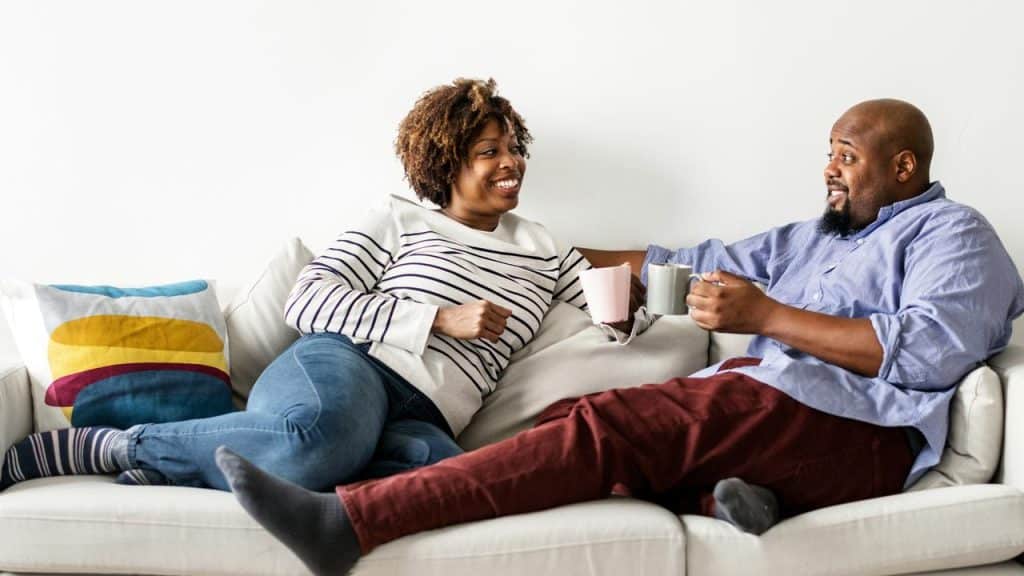 A couple on a couch holding mugs.