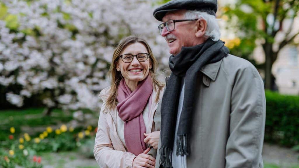 A woman and an elderly man walking together outdoors.