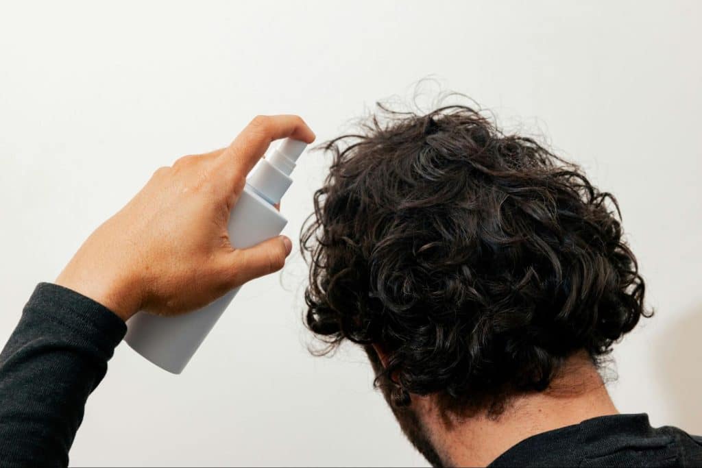 A man spraying something on his hair