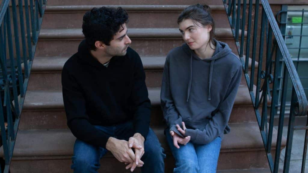 A man and woman sitting on brownstone steps, talking.